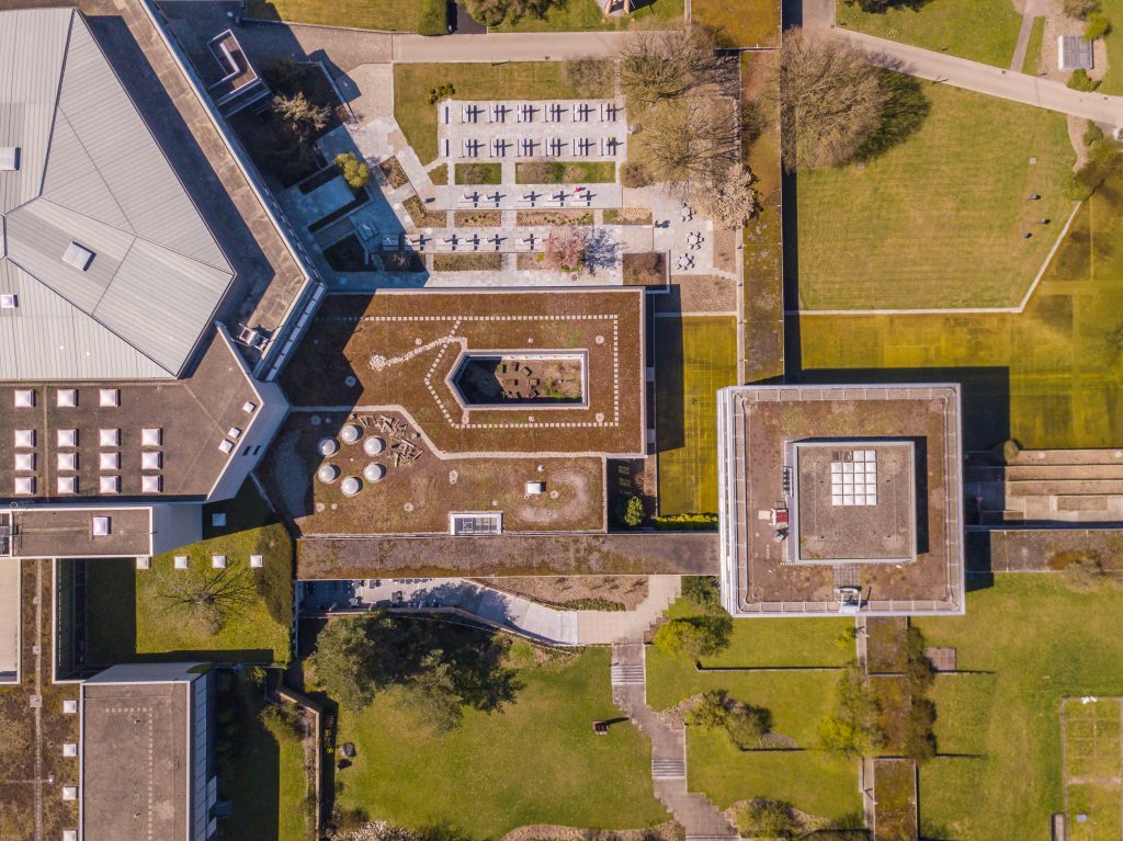 Aerial View Of University Buildings. Overhead Shot Of Building Roofs In Park Environment.